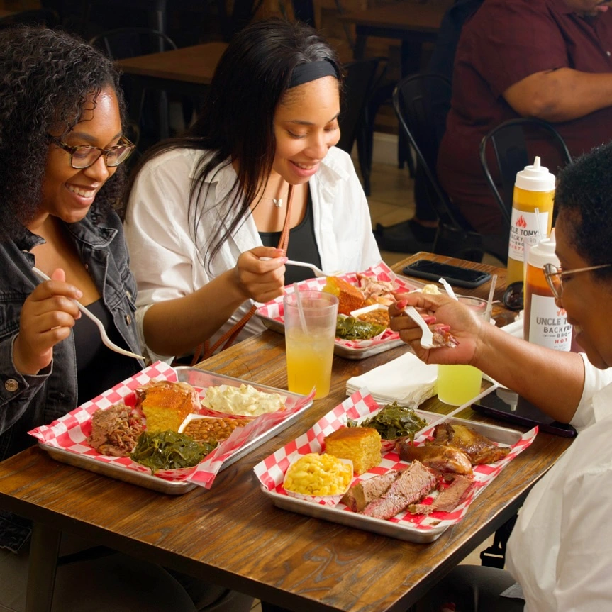 Three women enjoying a meal together at a table, engaged in conversation and sharing a pleasant dining experience.