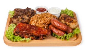 A wooden tray displaying an assortment of meat, fresh vegetables, and various sauces arranged artfully.